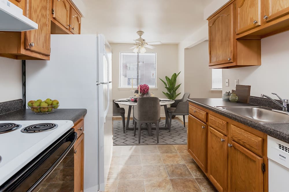 A cozy kitchen and dining area with wooden cabinets, modern appliances, and a small dining table with chairs by the window.