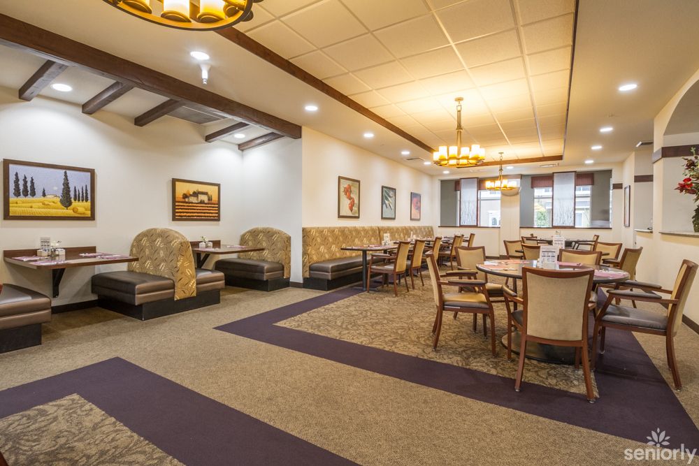 A cozy restaurant interior with various seating options, including tables, chairs, and booths, under warm lighting.