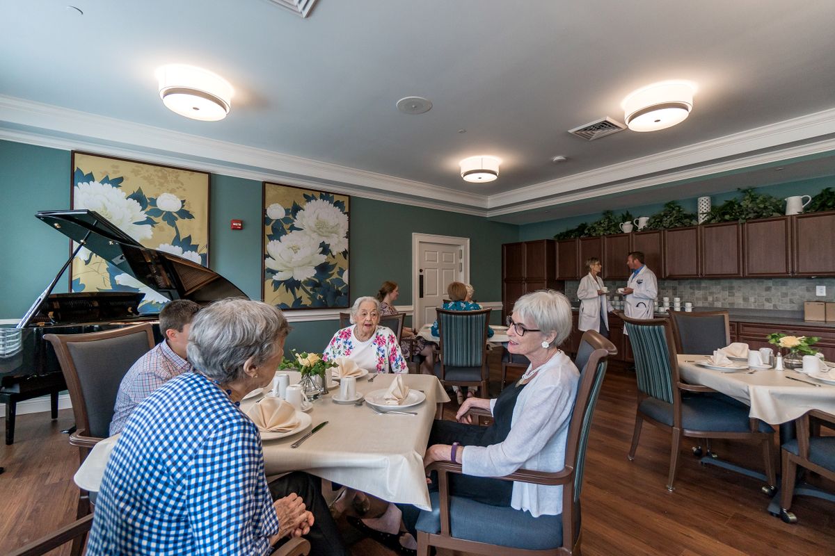 A group of elderly individuals socializing in a communal dining room.