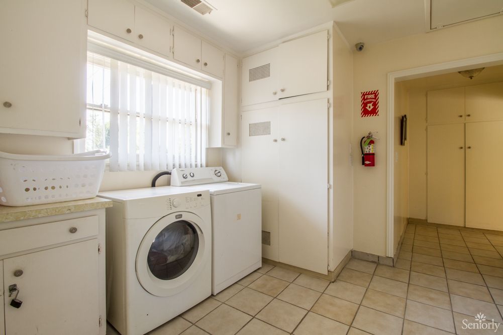 A bright laundry room with a washing machine, dryer, and built-in cabinets.