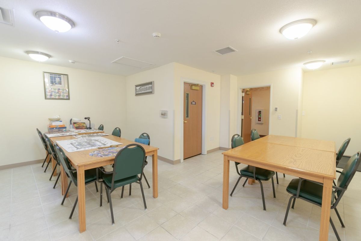 A clean, well-lit room with tables and chairs arranged for a meeting.
