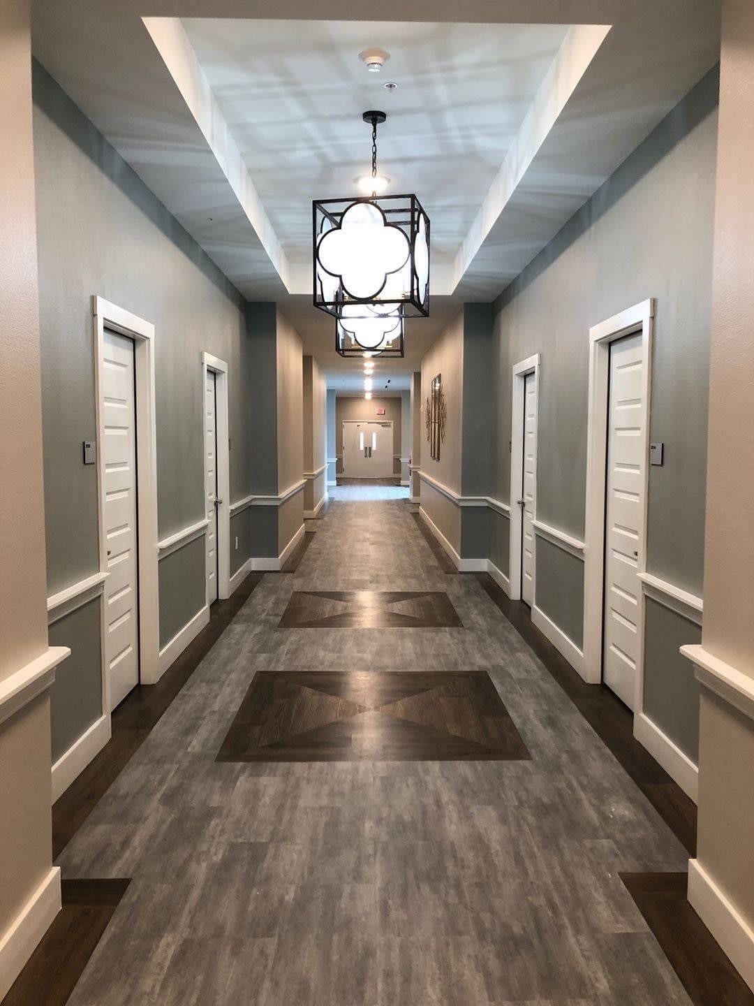A modern hallway with multiple doors and elegant lighting fixtures.