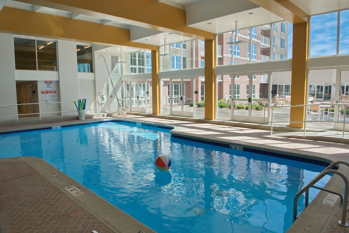A modern indoor swimming pool with natural light streaming through large windows.