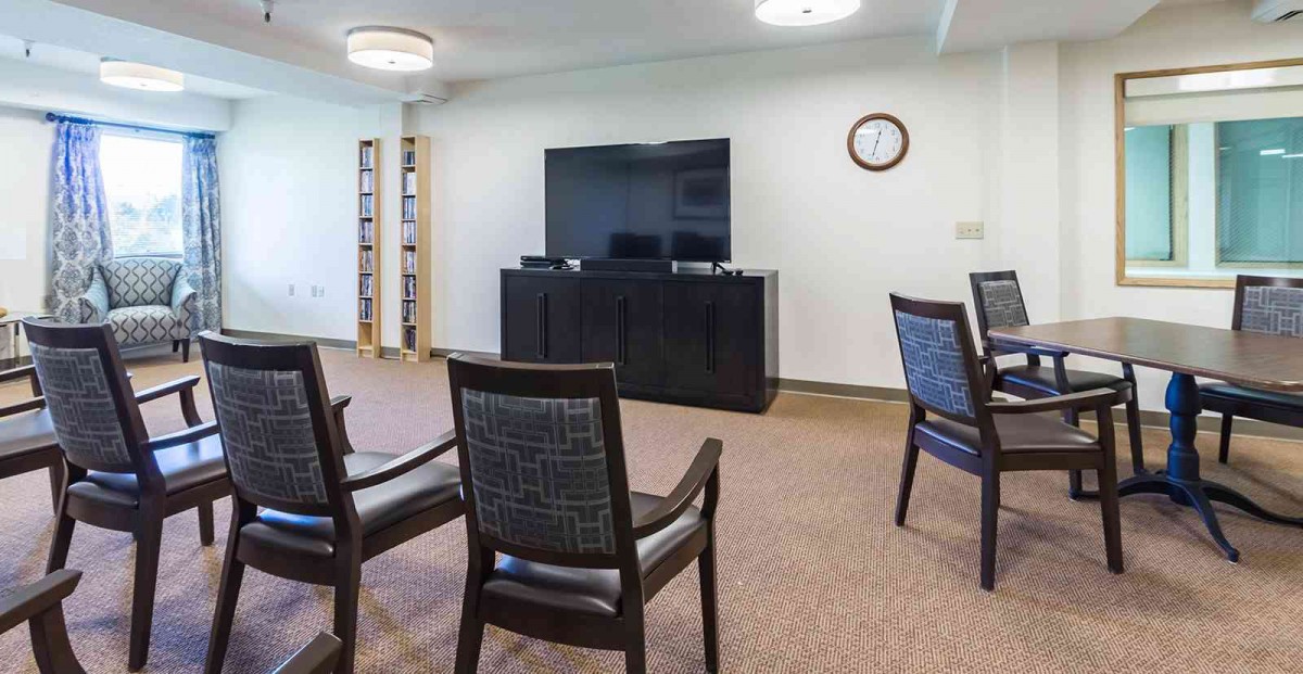 A meeting room with chairs arranged in front of a television and a bookshelf.