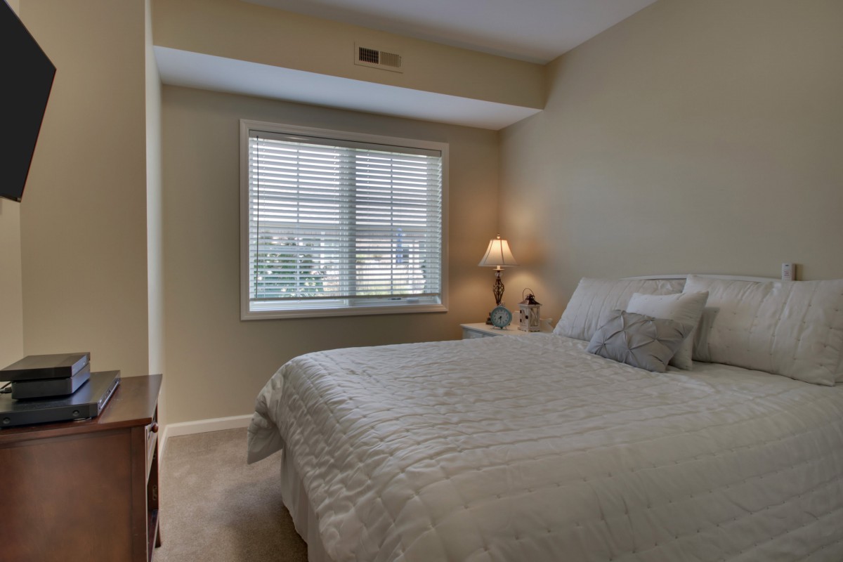 A cozy bedroom with a neatly made bed and a lamp by the window.