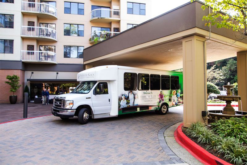 A shuttle bus parked under the entrance of a hotel building.