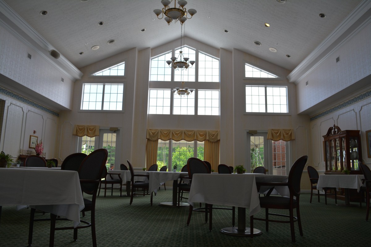 A spacious dining room with high ceilings, large windows, and elegantly arranged tables and chairs.
