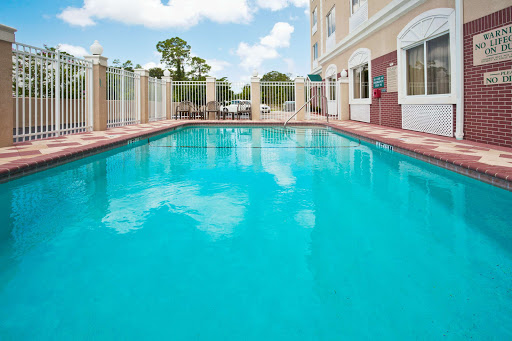 A serene outdoor swimming pool surrounded by greenery and a clear blue sky.