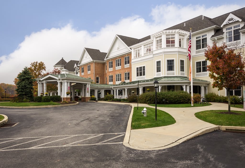 A large, multi-story residential building with a landscaped driveway and an American flag.
