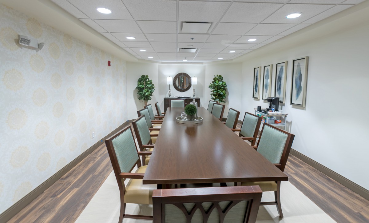 A conference room featuring a long meeting table with chairs, decorated with plants and artwork.