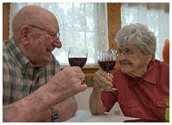 An elderly couple enjoying a glass of wine together, sharing a joyful moment.