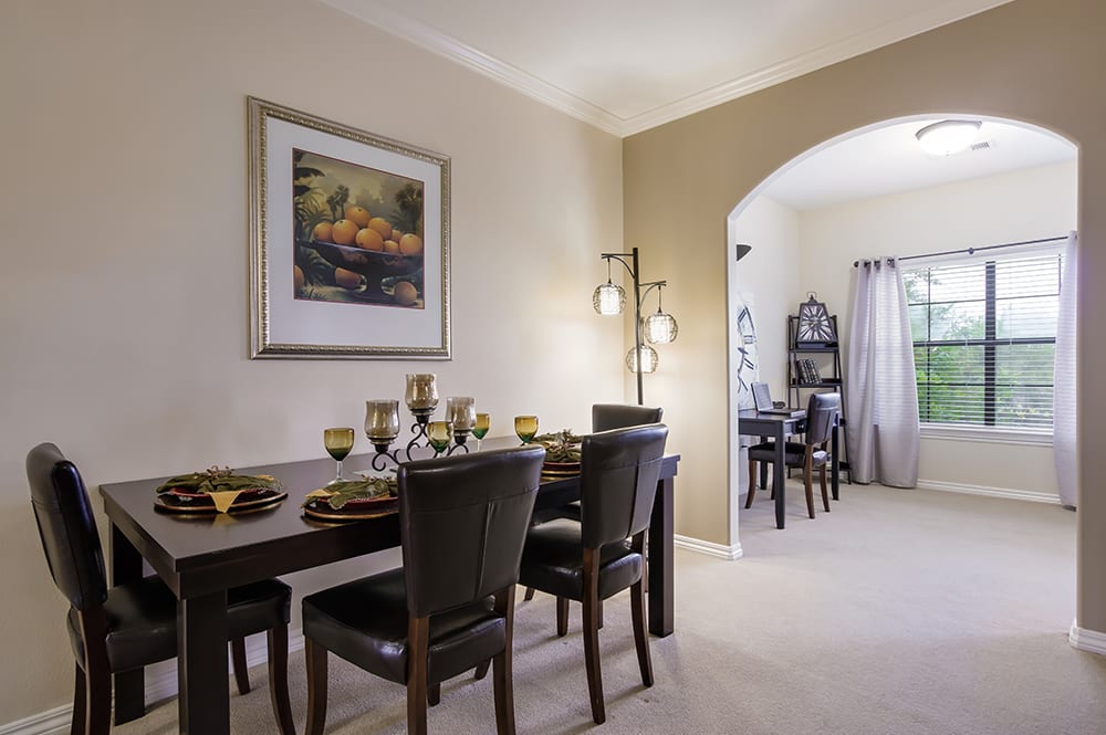 A modern dining room with a set table and elegant decor, featuring an archway leading to another room.
