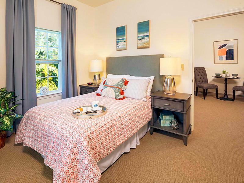A cozy bedroom with a neatly made bed, tasteful decor, and two bedside lamps.