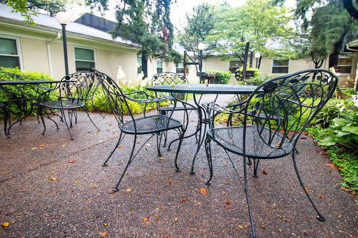 A cozy outdoor seating area featuring a metal table and chairs surrounded by lush greenery.