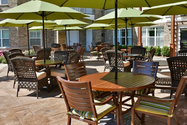 A well-arranged outdoor patio area with tables and chairs under green umbrellas.