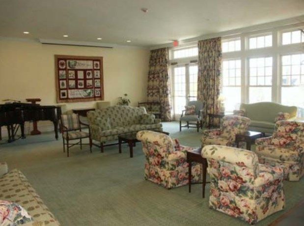 A cozy living room with floral-patterned furniture and large windows.
