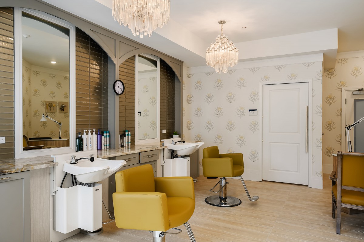 A stylish and modern hair salon with elegant chandeliers and comfortable seating.