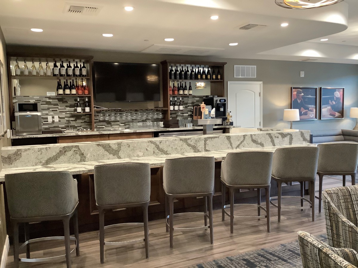 A modern bar interior with a marble countertop and neatly arranged stools.