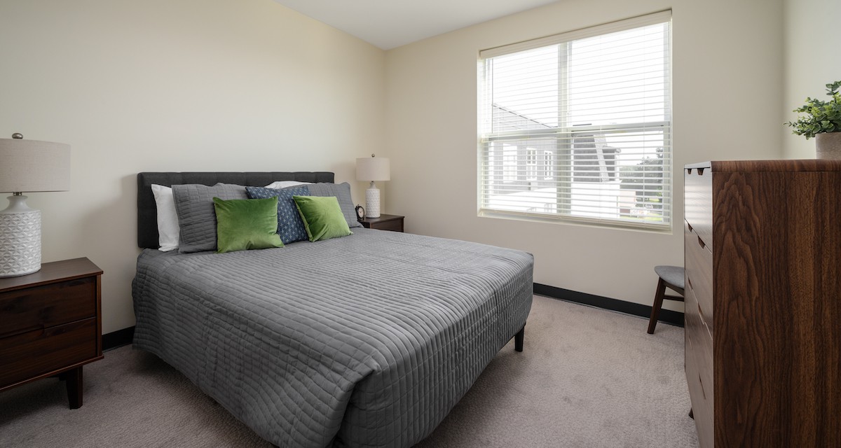 A minimalist bedroom with a bed, pillows, and a window.
