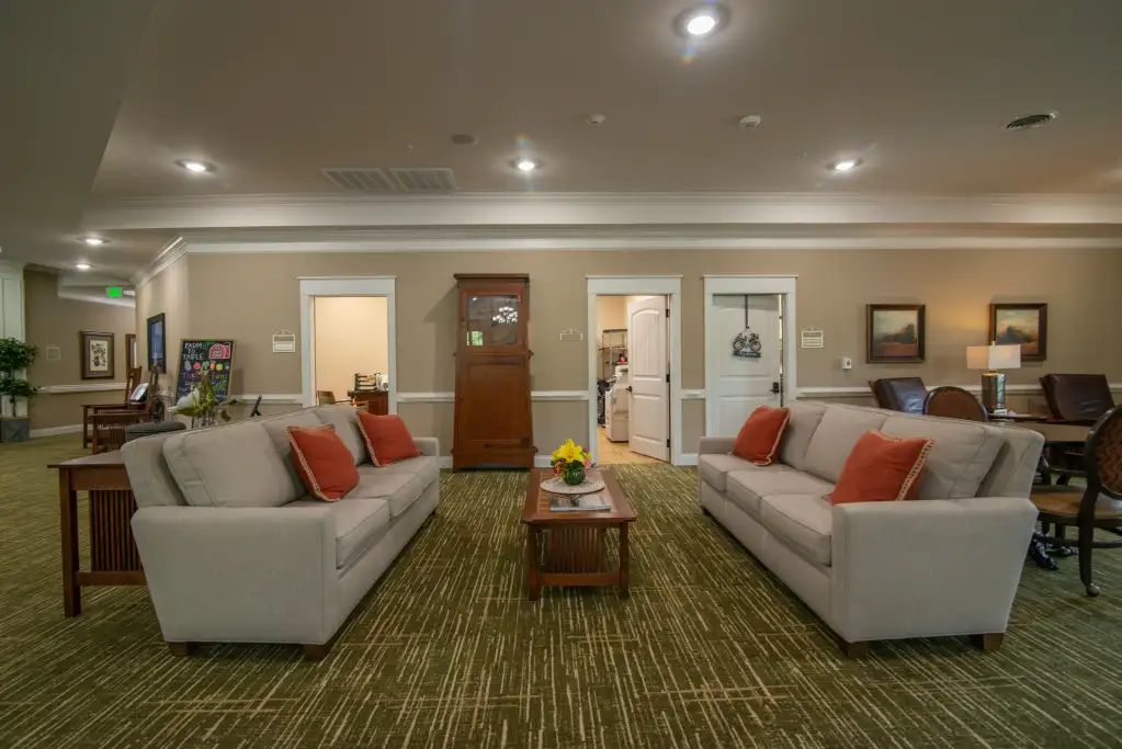 A cozy living room with two sofas facing each other, accented by orange pillows and a central coffee table.