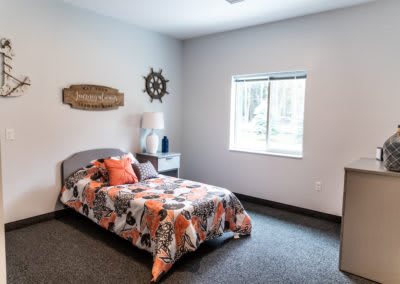 A cozy bedroom with a single bed, vibrant bedding, and decorative wall art.