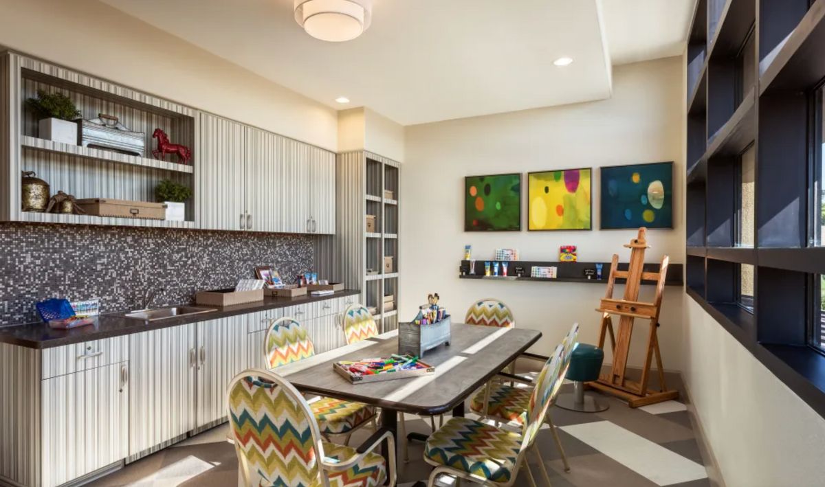 A vibrant art studio featuring colorful chairs, an easel, and various art supplies.