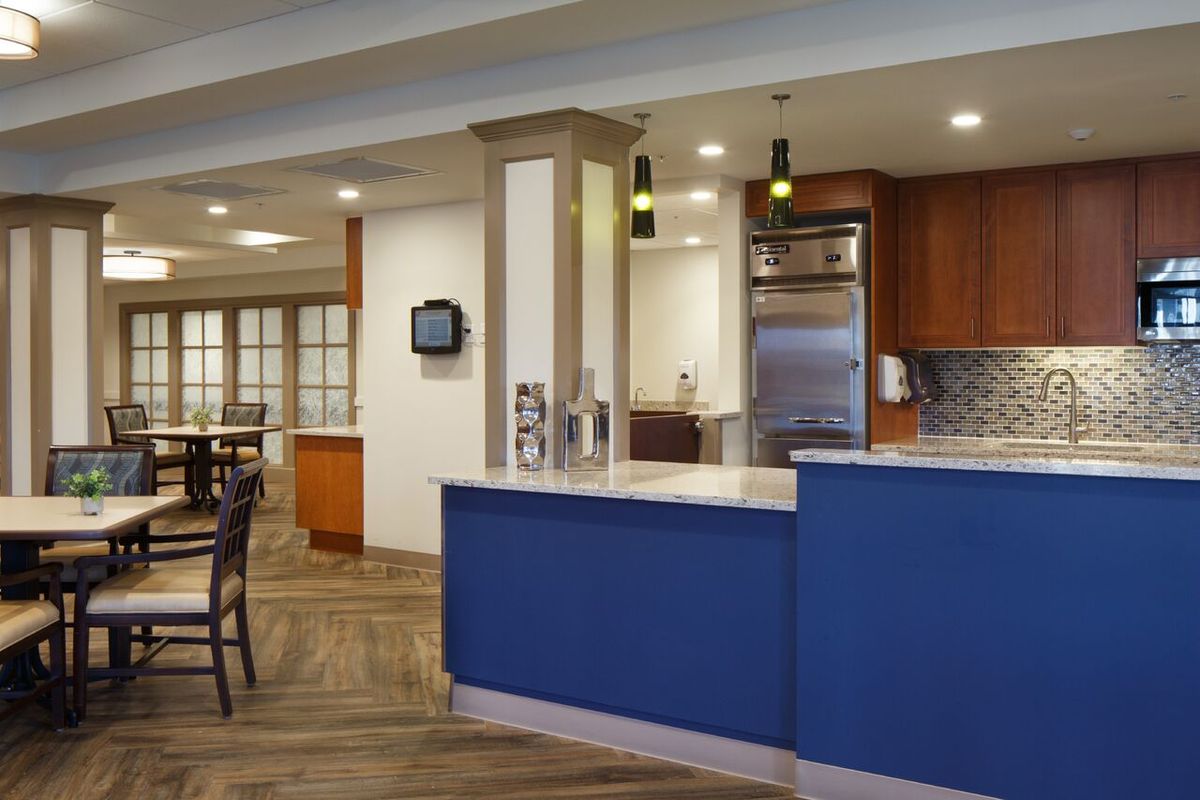 A modern kitchen and dining area with a blue counter and wooden accents.