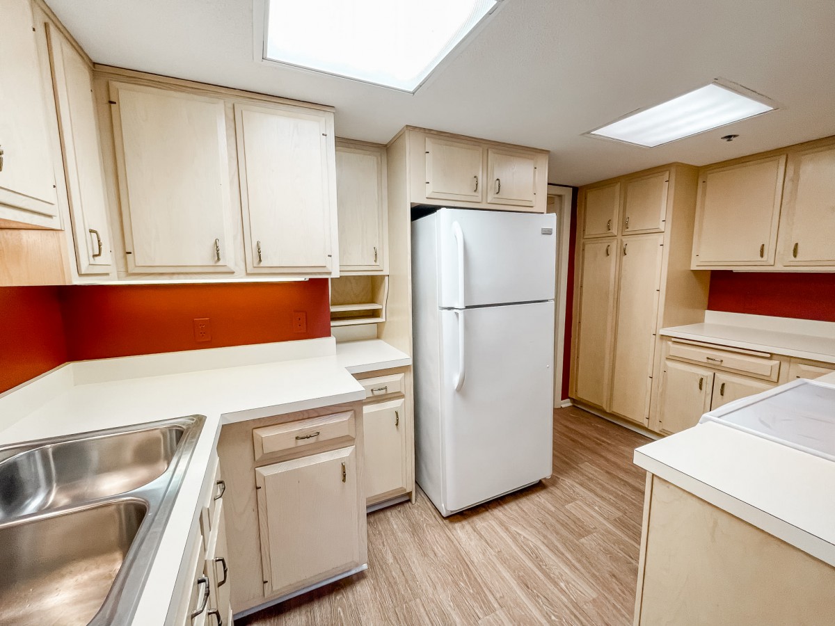 A modern kitchen with white cabinetry and a large refrigerator.