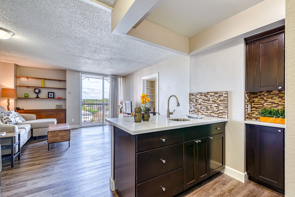 A modern open-concept kitchen with an island, adjacent to a cozy living area featuring hardwood floors and large windows.