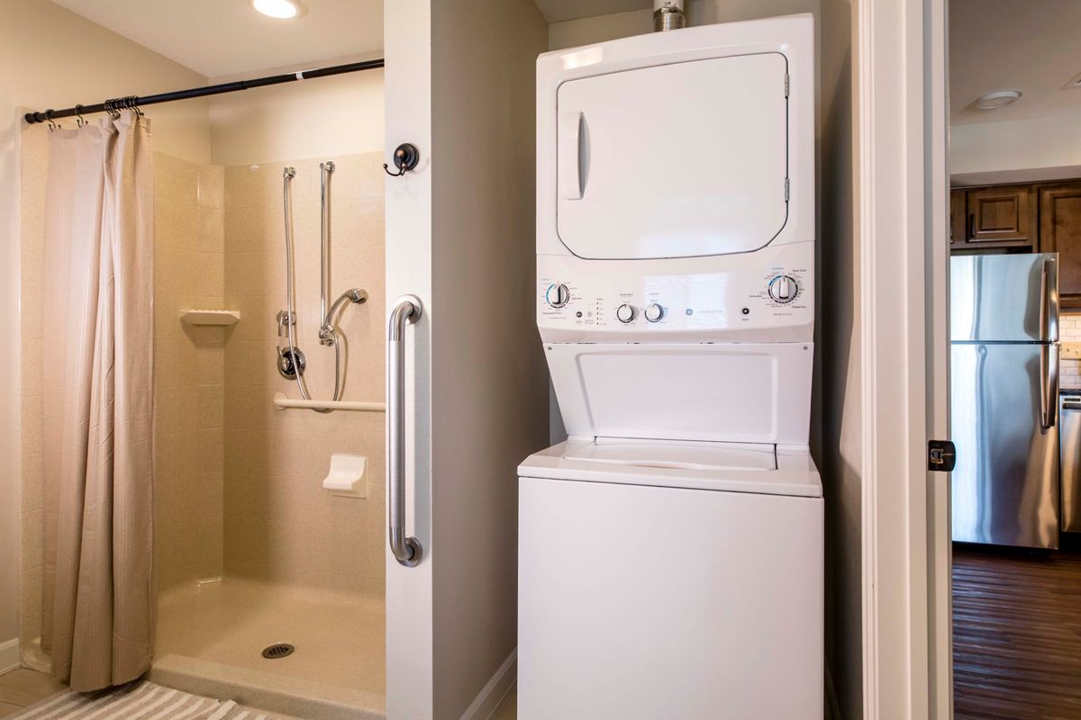 A compact bathroom with a stacked washer and dryer next to a shower.