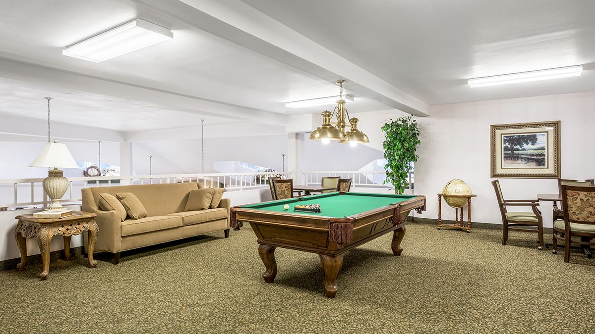 A cozy game room featuring a pool table, comfortable seating, and elegant lighting.
