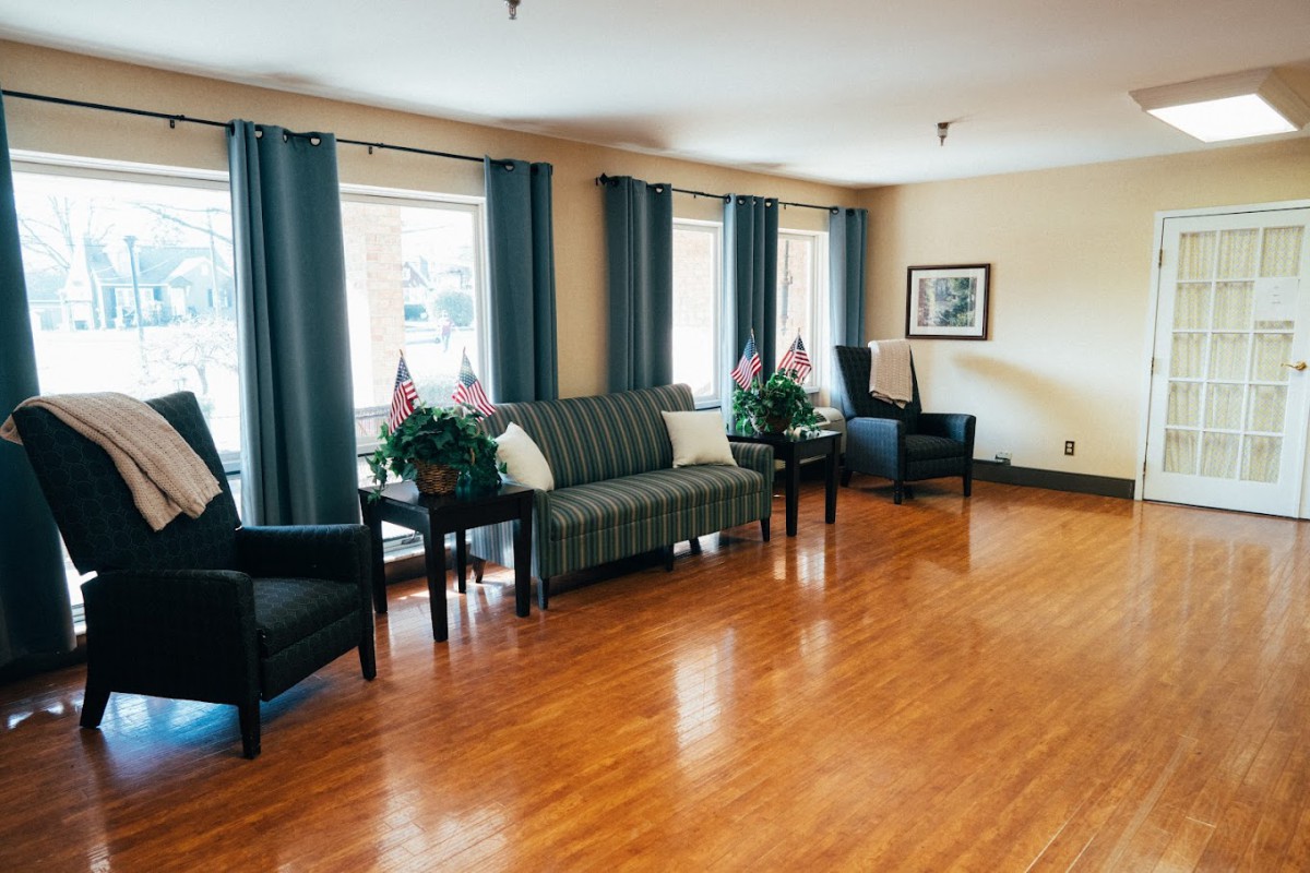 A well-lit living room with a sofa, chairs, and indoor plants on a hardwood floor.