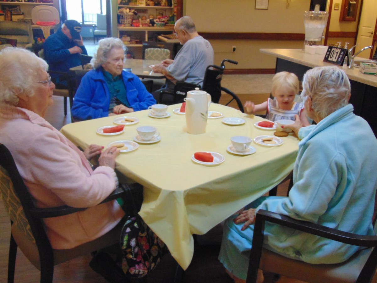 A group of elderly individuals enjoying a social gathering over tea indoors.