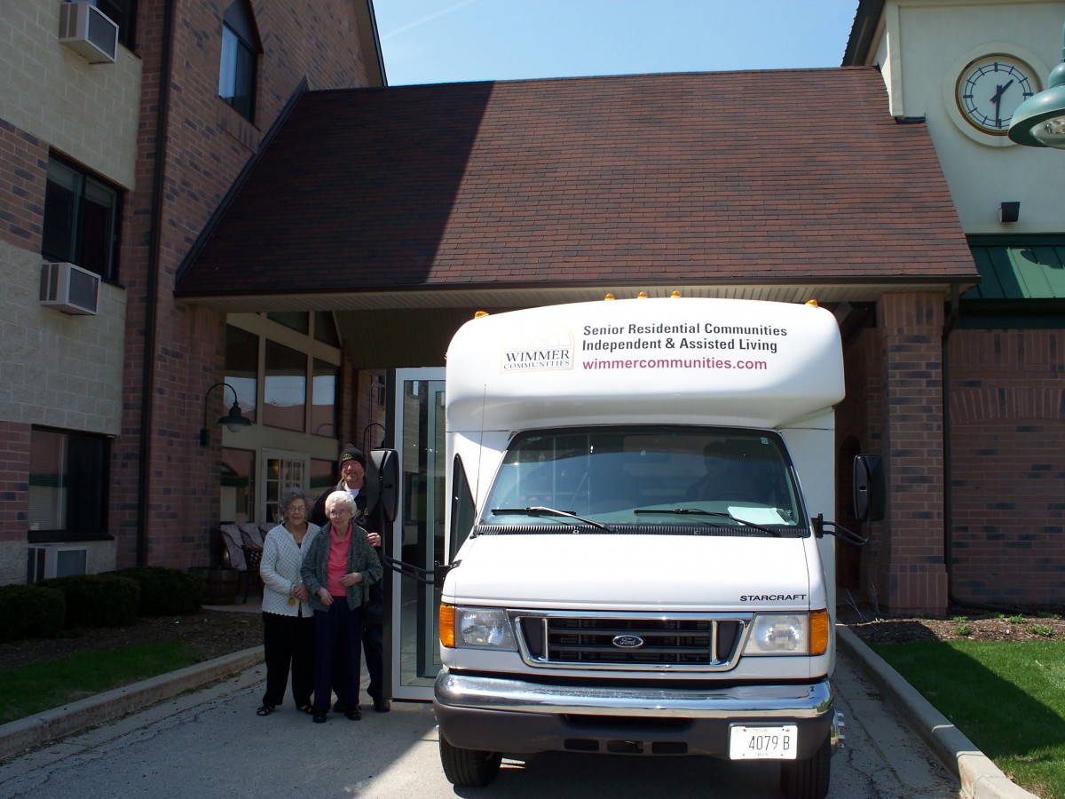 A group of people stands near a white van parked in front of a building.
