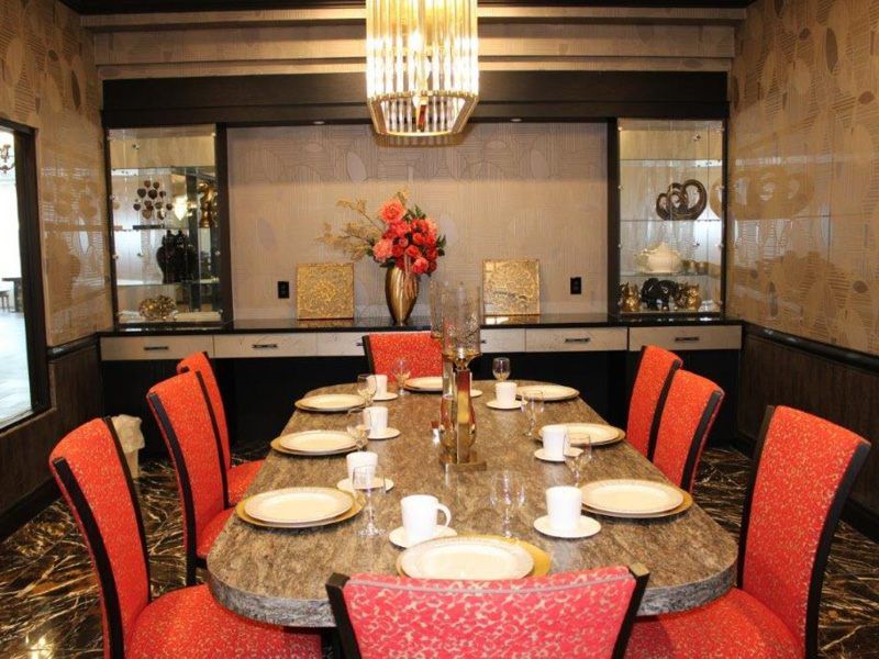 An elegantly decorated dining room with a set table and vibrant red chairs.