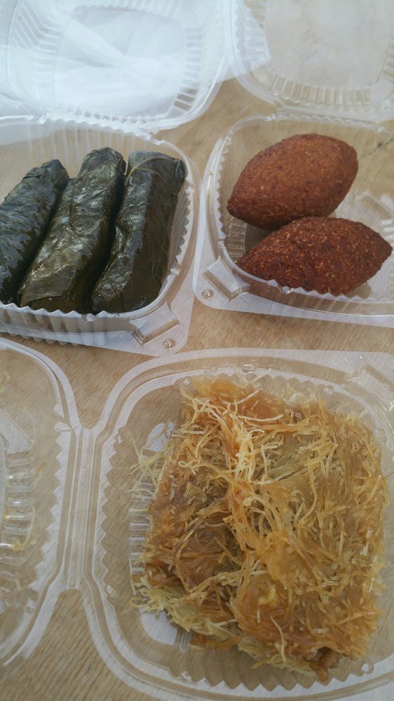 A selection of Middle Eastern dishes including dolma, kibbeh, and a sweet dessert.
