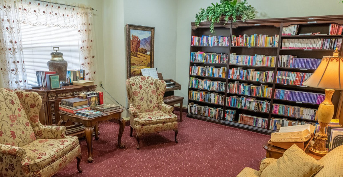 A cozy library corner with a bookshelf and a floral armchair.