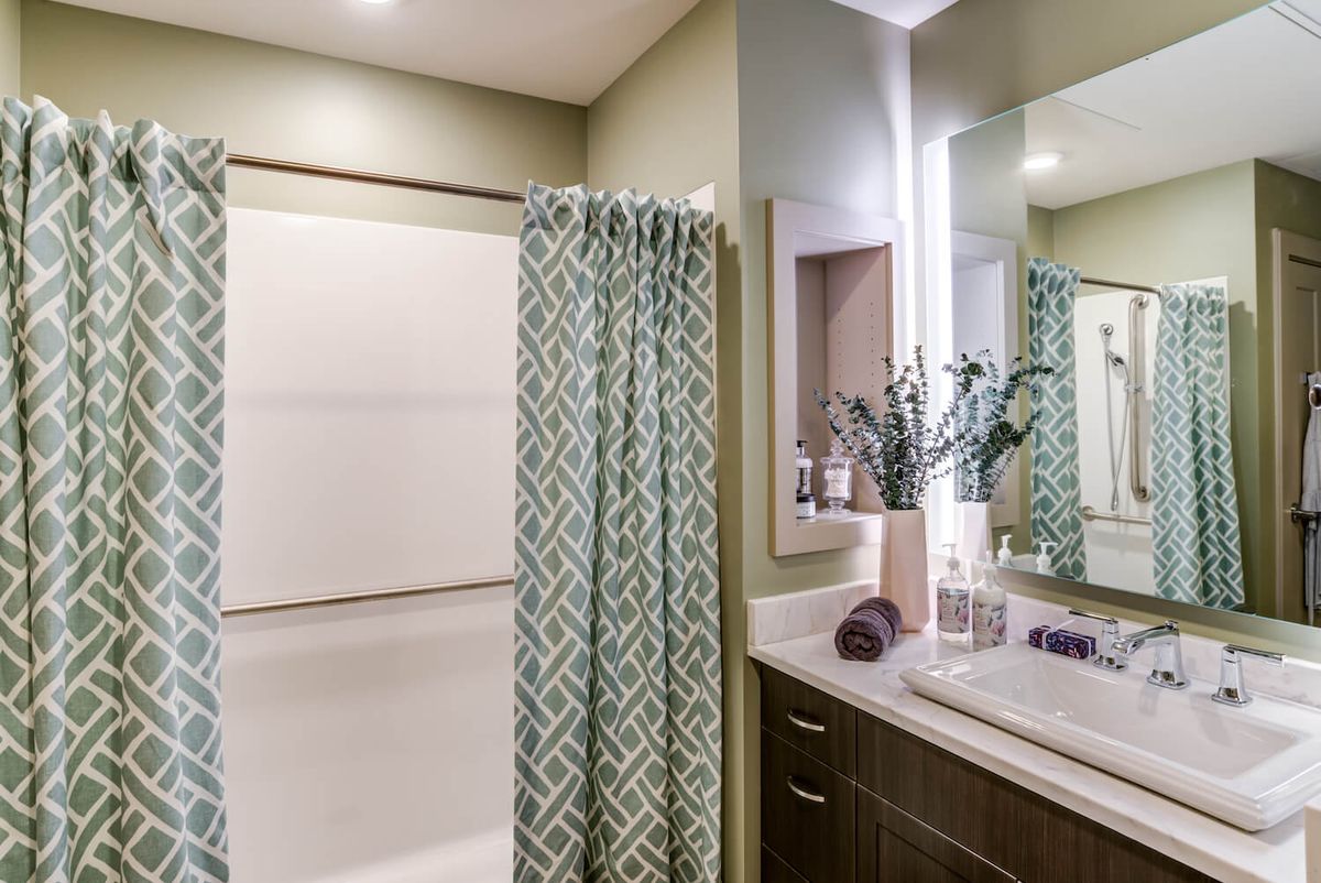 A modern bathroom featuring a geometric shower curtain and stylish decor.