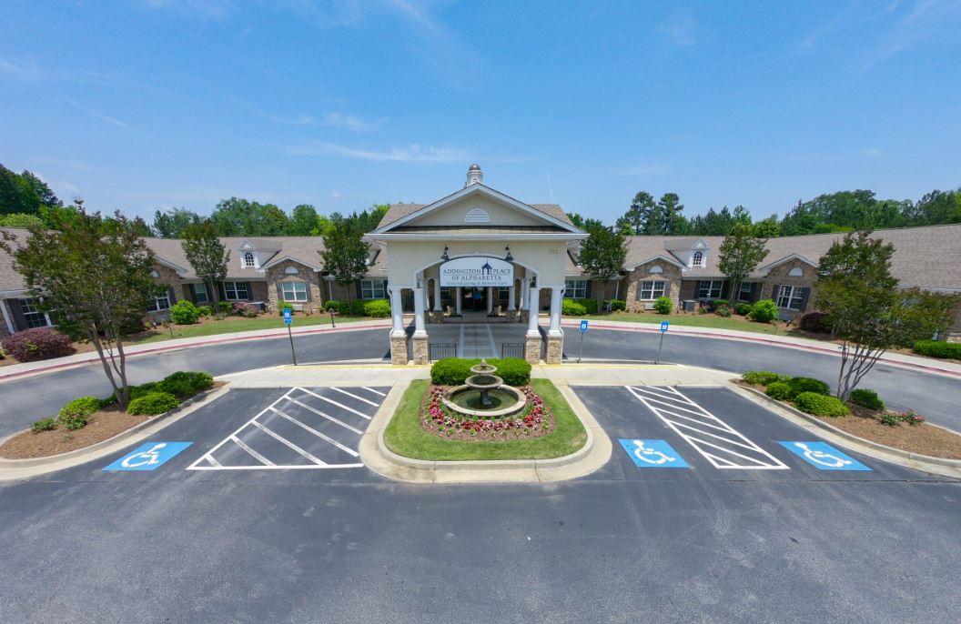 A symmetrical entrance to a large building with landscaped surroundings and a parking lot.