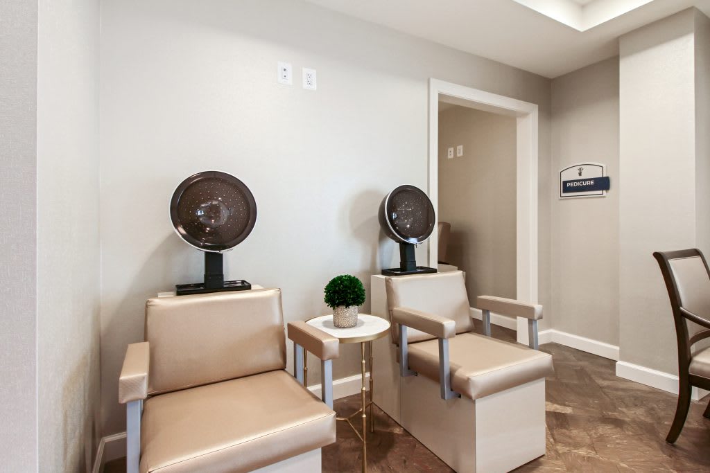 A modern salon with two hair drying chairs and a small table.