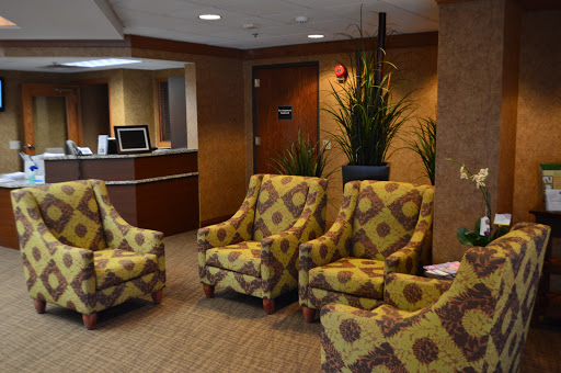 A cozy waiting area with patterned chairs and potted plants, perfect for relaxing while waiting.