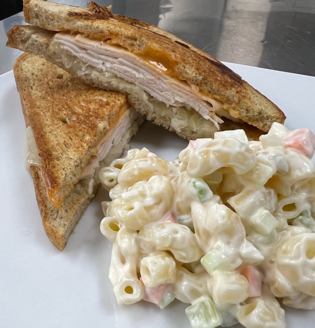 A plate featuring a grilled cheese sandwich and a side of pasta salad.