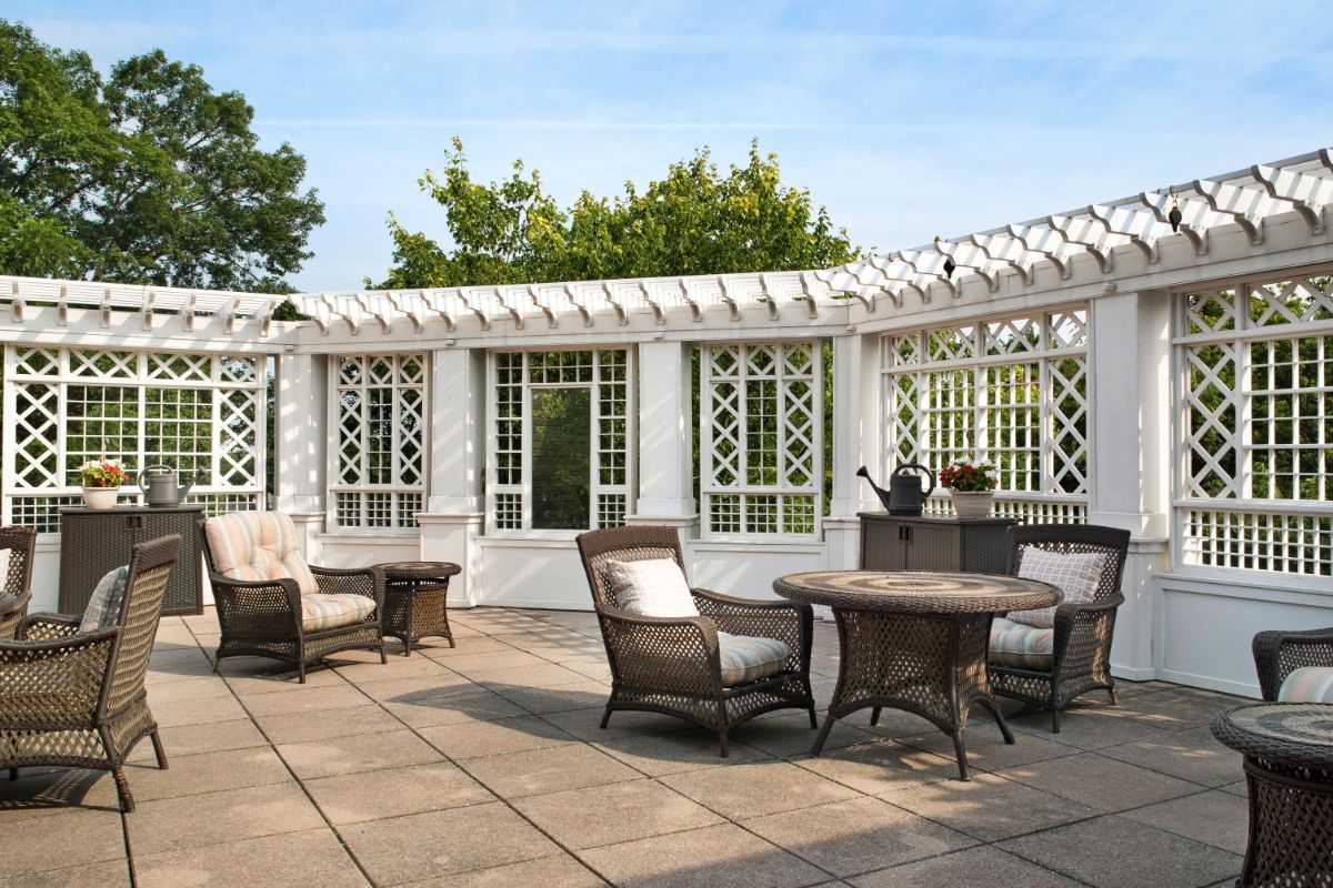 A stylish patio with wicker furniture and a white pergola, ideal for outdoor relaxation.