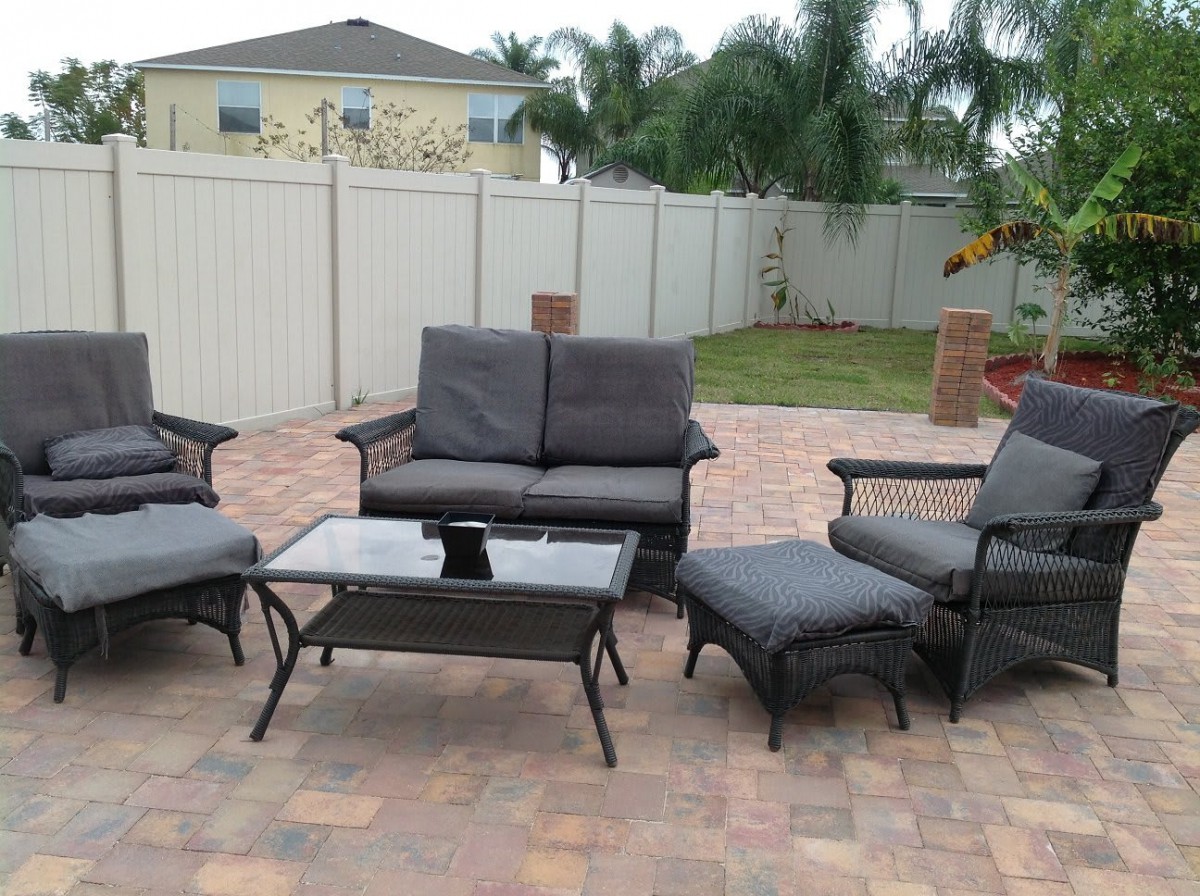 A set of outdoor patio furniture consisting of sofas, chairs, and a table in a backyard setting.