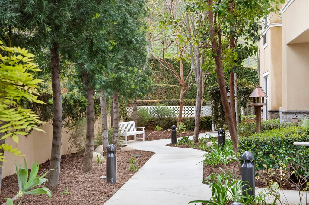 A serene garden pathway with benches surrounded by trees.