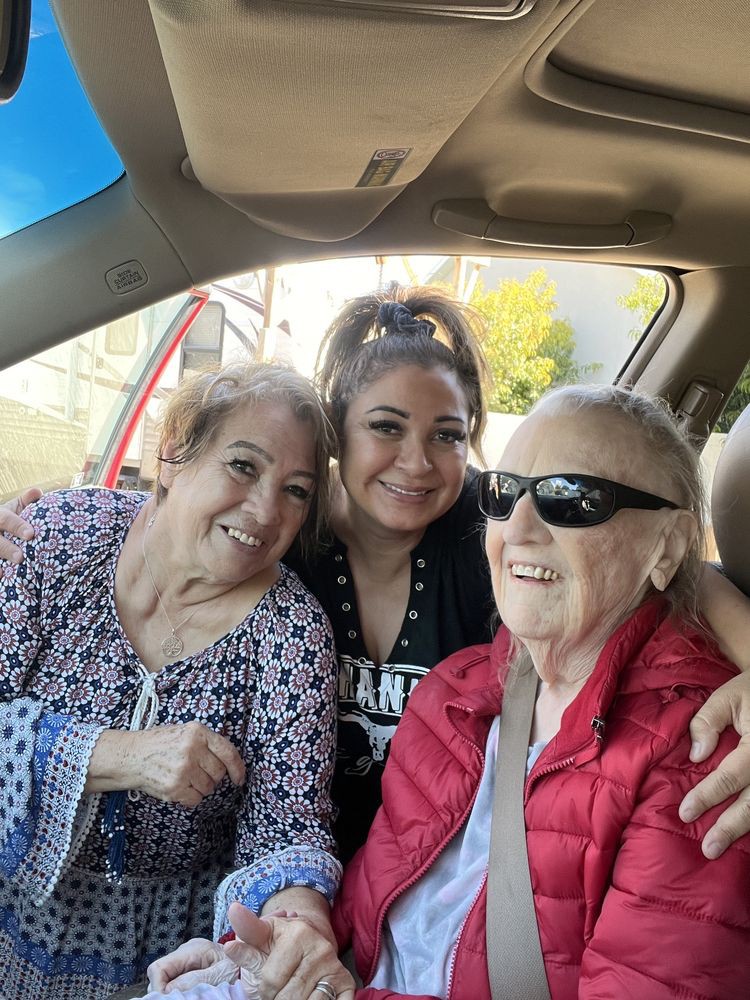 Three people smiling and sitting together in a car, enjoying each other's company.