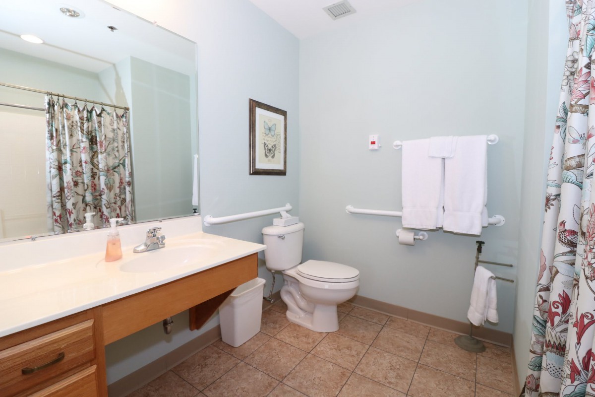 A clean, well-lit bathroom with a toilet, sink, and mirror.