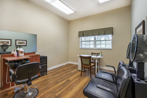 A neatly arranged salon room with chairs, a mirror, and a window.