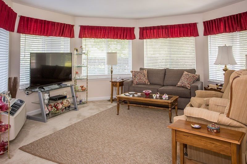 A cozy living room with a sofa, television, and coffee table, accented by red curtains.