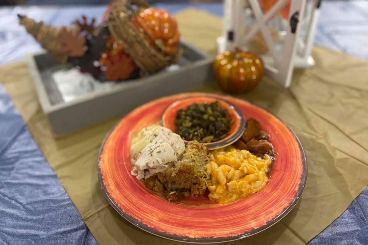 A plate of comfort food with mac and cheese, greens, mashed potatoes, and fried chicken surrounded by autumn decorations.